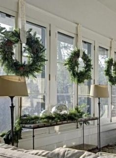 a living room filled with lots of windows covered in christmas wreaths and greenery