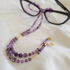 Beautiful, dainty, and luxurious. This amethyst eyeglass chain will complement your favorite pair of eyeglasses or sunglasses. *This eyeglass chain is approx. 26 inches.   *Made with faceted amethyst beads in 2 sizes,  permagold  seed beads, Swarovski crystals and gold plated tubes . *Featuring gold plated clasps and jewelry wire.  *includes 1 pair of clear with gold eyeglass loops AND 1 pair of black with gold eyeglass loops  This chain is a head turner! Adjustable Purple Glass Glasses Chains, Purple Glass Glasses Chains As Gift, Elegant Adjustable Glasses Chains As Gift, Elegant Glasses Chains As A Gift, Elegant Adjustable Glasses Chains For Gifts, Beaded Eyeglass Chain, Glasses Chains, Sunglass Chain, Eyeglass Chain