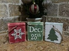 three wooden christmas signs sitting on top of a counter