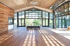 the inside of a building with wooden floors and large glass windows on each side of it