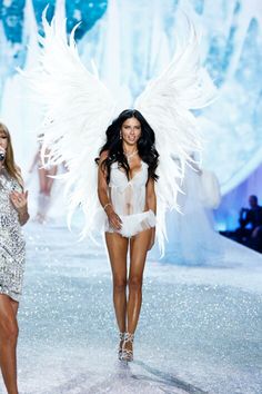 two models walk down the runway with angel wings