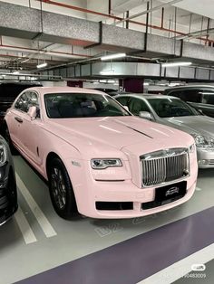 several cars parked in a parking garage with one pink car and the other silver car