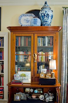 an antique china cabinet with blue and white vases on top in a living room