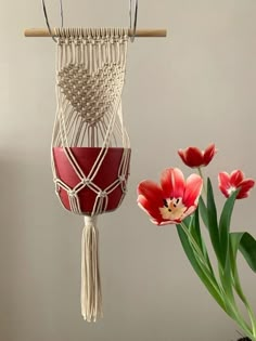 a macrame hanging on a wall next to a potted plant and tulips