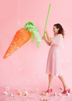 a woman is holding a carrot shaped object in front of confetti and streamers