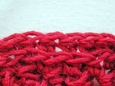 a red crocheted bag sitting on top of a white cloth covered in yarn