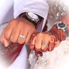 a man and woman holding hands with wedding rings on their fingers, both wearing matching watches