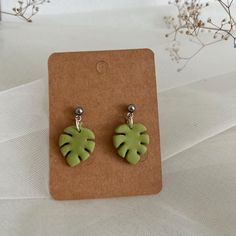 a pair of earrings with green leaves on them