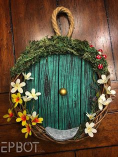 a green door with flowers on it and a rope hanging from the front is surrounded by wood planks