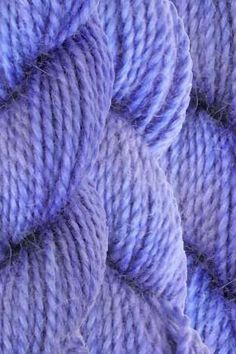 purple yarn is piled up in rows