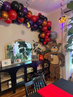 a party room with balloons and decorations on the wall, including a large teddy bear