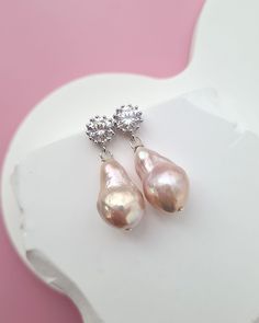 Lustrous light metallic pink baroque pearl earrings showcasing the natural romantic and subtle light pink color of the pearls. Minimalistic design matched with the high lustre and radiance making a statement without being over-stated. Perfect for everyday wear and special occasions alike.  ✧ Baroque Pearl size: around 10mm x 17 mm ✧ Pearl Color: Light Metallic Pink Color, as shown in pictures ✧ Shape: Baroque with slight wrinkles ✧ Surface: good lustre, smooth surface with baroque characteristics , as shown in pictures ♡ Pearl Earrings FWPE026_4 ♡  ✧ Earrings length: around 1.1 inch ✧ White gold plated cubic zirconia ear post with sterling silver ear pins ✧ Sterling Silver findings. ✧ For video, you can visit my Instagram @glitzandlove. For a closer look, refer to the video on Instagram @g Feminine Pink Pearl Earrings, Feminine Pink Pearl Drop Earrings, Handmade Pink Pearl Drop Earrings, Adjustable Pink Pearl Drop Earrings, Pink Baroque Pearl Drop Jewelry, Baroque Pearls Jewelry, Tahitian Pearls Jewelry, Pearl Jewelry Gift, Freshwater Pearl Jewelry