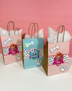 three paper bags with paw patrol designs on them, one is pink and the other is blue