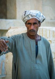 a man with a turban on his head standing in front of a building