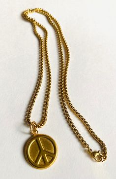 Long Peace Necklace Plated brass. Sturdy coin size charm of brass. Peace sign design. Sturdy long 22" gold over steel chain. Steel lobster clasp. Super fun to wear and layer with other necklaces. Long Peace Necklace Gold Round Medallion Necklace, Vintage Yellow Gold Coin Necklace With Adjustable Chain, Vintage Gold-plated Tarnish-resistant Charm Necklaces, Vintage Gold Plated Tarnish Resistant Charm Necklace, Vintage Gold-plated Tarnish-resistant Charm Necklace, Tarnish Resistant Bronze Brass Necklace, Vintage Brass Chain Necklace Tarnish Resistant, Vintage Gold Coin Necklace With Chain, Vintage Tarnish Resistant Brass Chain Necklace