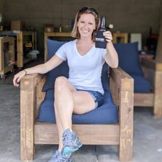 a woman sitting in a chair holding up a bottle