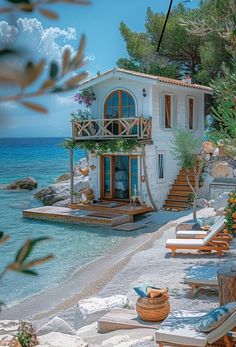 a house on the beach with lounge chairs and trees around it, overlooking the water