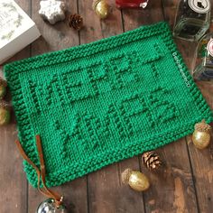 a green knitted placemat sitting on top of a wooden table next to christmas decorations