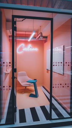 an office with pink walls, black and white striped flooring and a neon sign on the wall