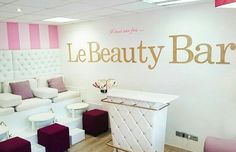 the interior of a beauty salon with pink and white furniture