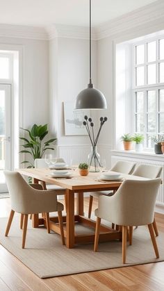 a dining room table with chairs around it and a potted plant in the corner