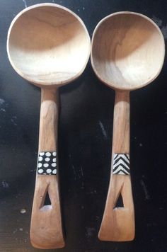 two wooden spoons with black and white designs on them