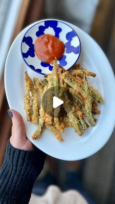 a person holding a plate with food on it and ketchup in the middle