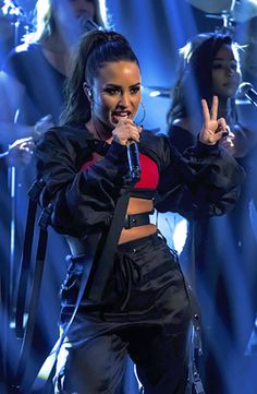 a woman standing on top of a stage holding a microphone in front of her face