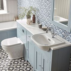 a white toilet sitting next to a bath tub under a bathroom mirror above a sink