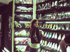 a woman standing in front of a rack of shoes