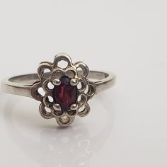 Dainty silver ring with flower shape. Double layer of open framed petals with central prong set glass simulated garnet oval gem. Marked 925 and CA.  Size US 5 3/4.  Previously owned and in good condition. There are minor signs of age/use to the band. The pictures are part of the description.  Do browse our other items. We combine shipping for savings. International purchasers can contact the shop for a quote to the shipping address. Garnet Stone, Ring Oval, Stackable Ring, Silver Flowers, Stackable Rings, Flower Shape, Oval Cut, Prong Setting, Garnet