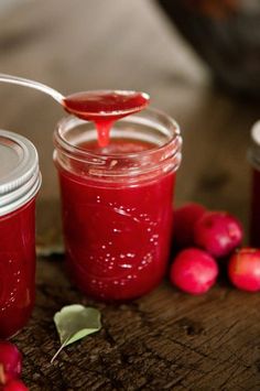 two jars filled with red liquid sitting on top of a wooden table