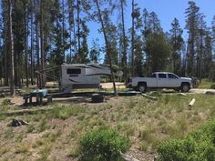 a truck parked next to a camper in the woods