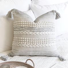 a white bed topped with pillows and a basket