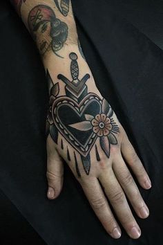 a person's hand with a tattoo on it and a heart in the middle