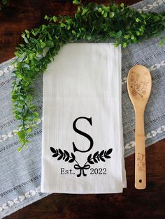 a tea towel with the letter s on it next to a wooden spoon