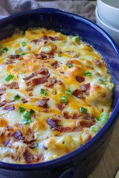 a casserole dish with bacon, cheese and green onions in a blue bowl