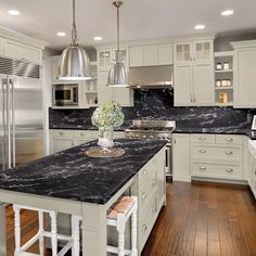 a large kitchen with marble counter tops and white cabinets, along with stainless steel appliances