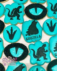 cookies decorated with blue frosting and black icing are arranged in the shape of godzillas