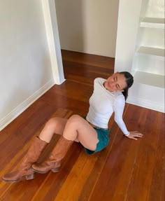 a woman is sitting on the floor with her legs spread out and wearing cowboy boots