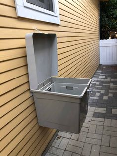 a gray trash can sitting on the side of a building