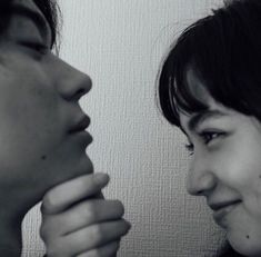 two women are looking at each other in black and white, one is holding her nose to the other's mouth