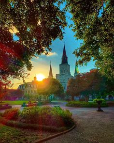 the sun is setting in front of a large building with steeples on it's sides