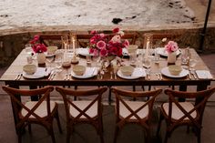 a table set with plates, cups and vases filled with flowers on top of it