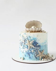 there is a blue and white cake with starfish on the top, and seashells on the bottom