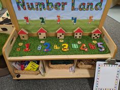 a wooden toy bench with numbers and houses on the grass for children to play in