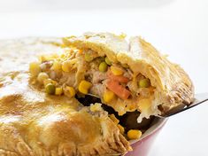 a piece of chicken pot pie with a spoon in it's mouth on a white surface