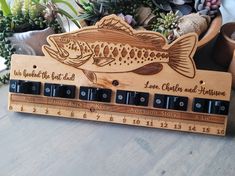 a wooden ruler with a fish on it and some succulents in the background