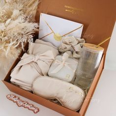 a box filled with baby's clothes next to a vase and some dry grass