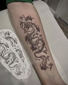 a black and white photo of a dragon tattoo on the left leg, next to a piece of paper